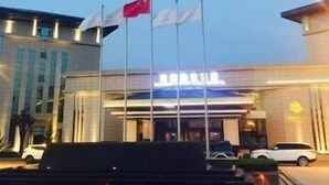 Ein Hotel mit zeitgemäßem Äußeren, mehreren Flaggen und einem gut beleuchteten Eingang.