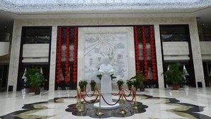 Eine geräumige Lobby mit hoher Decke und einem großen Kunstwerk in der Mitte.