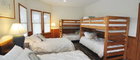 A room with bunk beds, a ceiling fan, and a lamp on a bedside table.