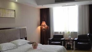 A hotel room with a large bed, a desk, two chairs, and a window with curtains. - Windsor Hotel (Zhangzhou)