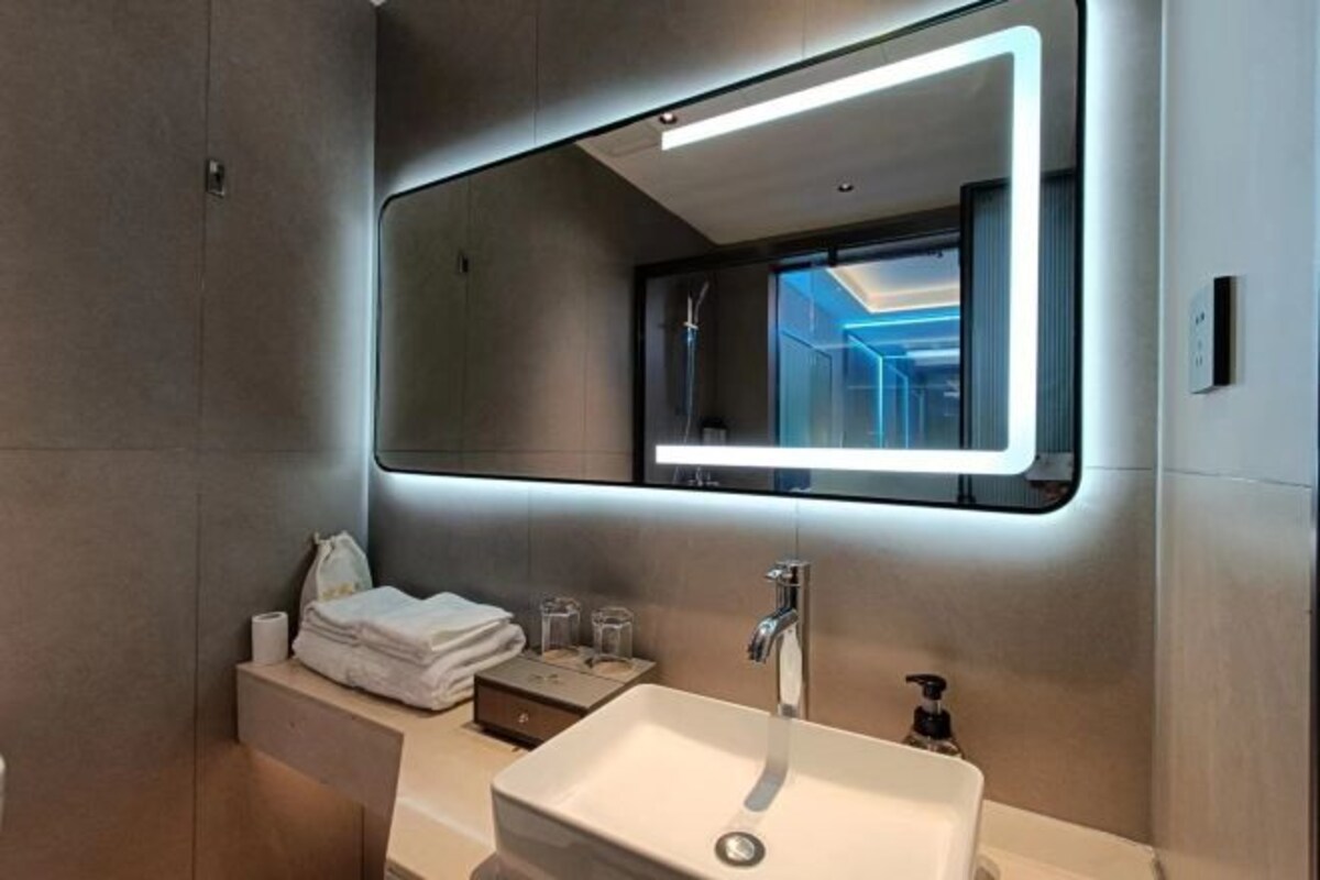 Un baño moderno con un espejo grande, un lavamanos y un perchero para toallas.