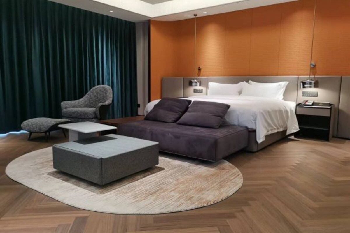 Un dormitorio moderno con cama, mesitas de noche, escritorio y una silla.