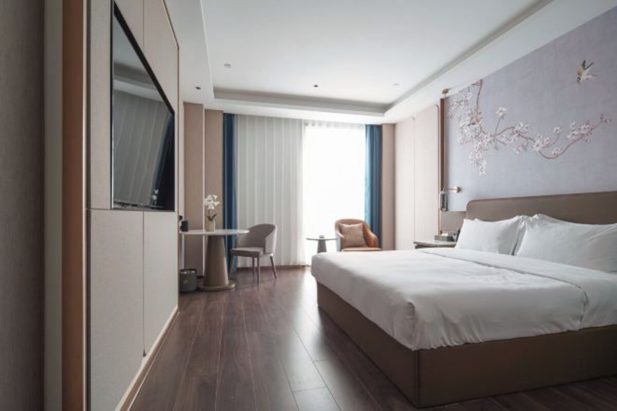 Una habitación de hotel moderna con una cama grande, un escritorio y una silla.