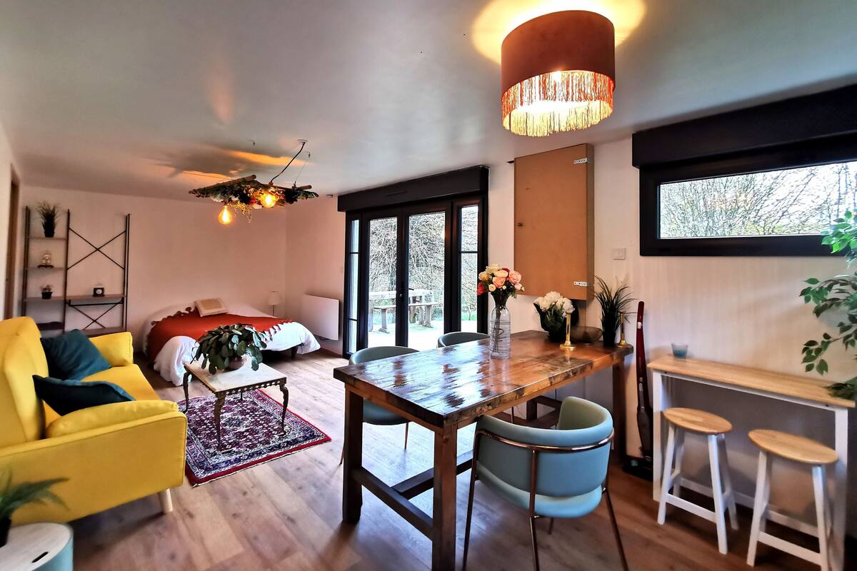 Een moderne woonkamer met een gele bank, een houten eettafel en een groot raam.