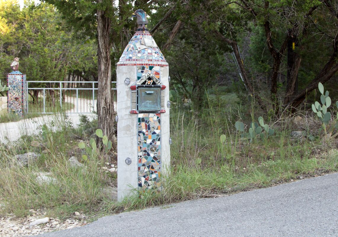 Une structure recouverte de mosaïques, ornée du chiffre « 709 » et dotée d’une petite fenêtre, le tout entouré de végétation naturelle.
