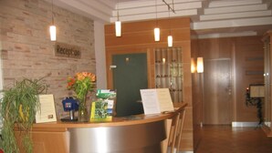 Un comptoir d’accueil en bois, une plante et des brochures d’information.
