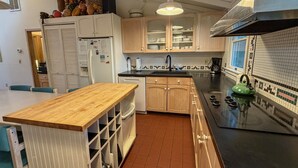 Una cucina con pensili in legno, un piano di lavoro nero, un bollitore verde e uno schienale piastrellato.