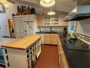 Una cocina con armarios de madera, encimera negra, hervidor verde y salpicadero azulejado.