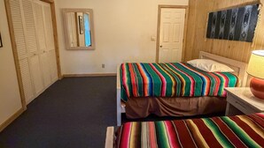 Una camera da letto con un letto, una ventola a soffitto, una porta e un'opera d'arte appesa al muro.