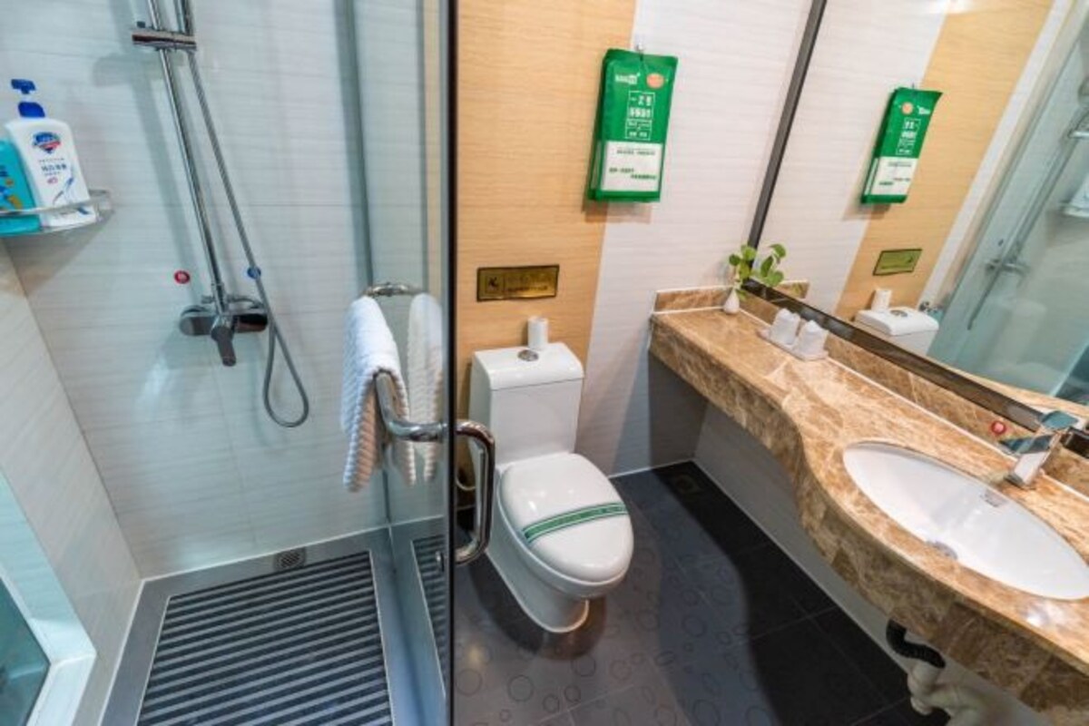 Une salle de bain moderne avec une douche à parois de verre, des toilettes, un lavabo doté d’un plan de travail en marbre et un miroir.