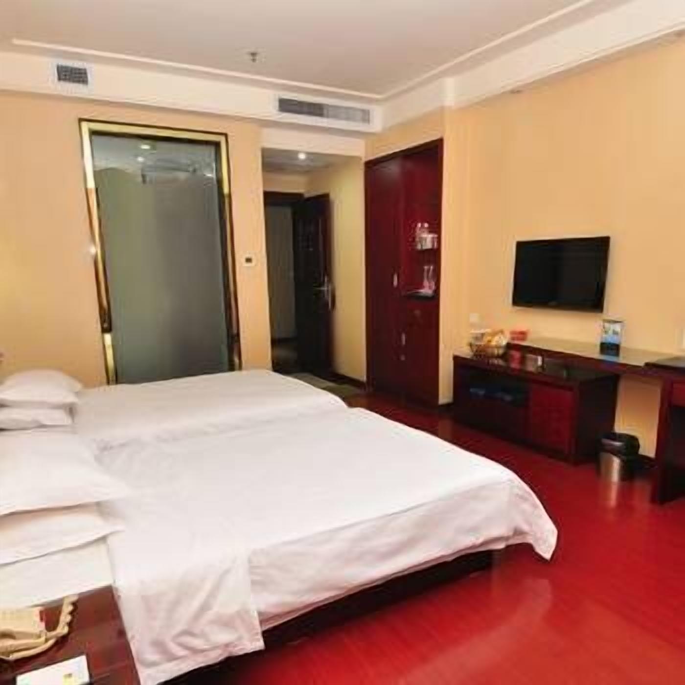A hotel room with a bed, a desk, a television, and a wardrobe.