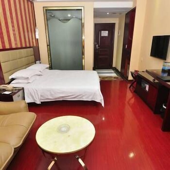 A hotel room with a bed, a sofa, a small round table, and a TV. - Adida Business Hotel (Guangzhou)