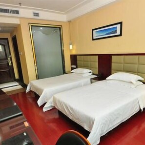 A hotel room with two single beds, a wooden floor, a door, and a framed picture on the wall. - Adida Business Hotel (Guangzhou)