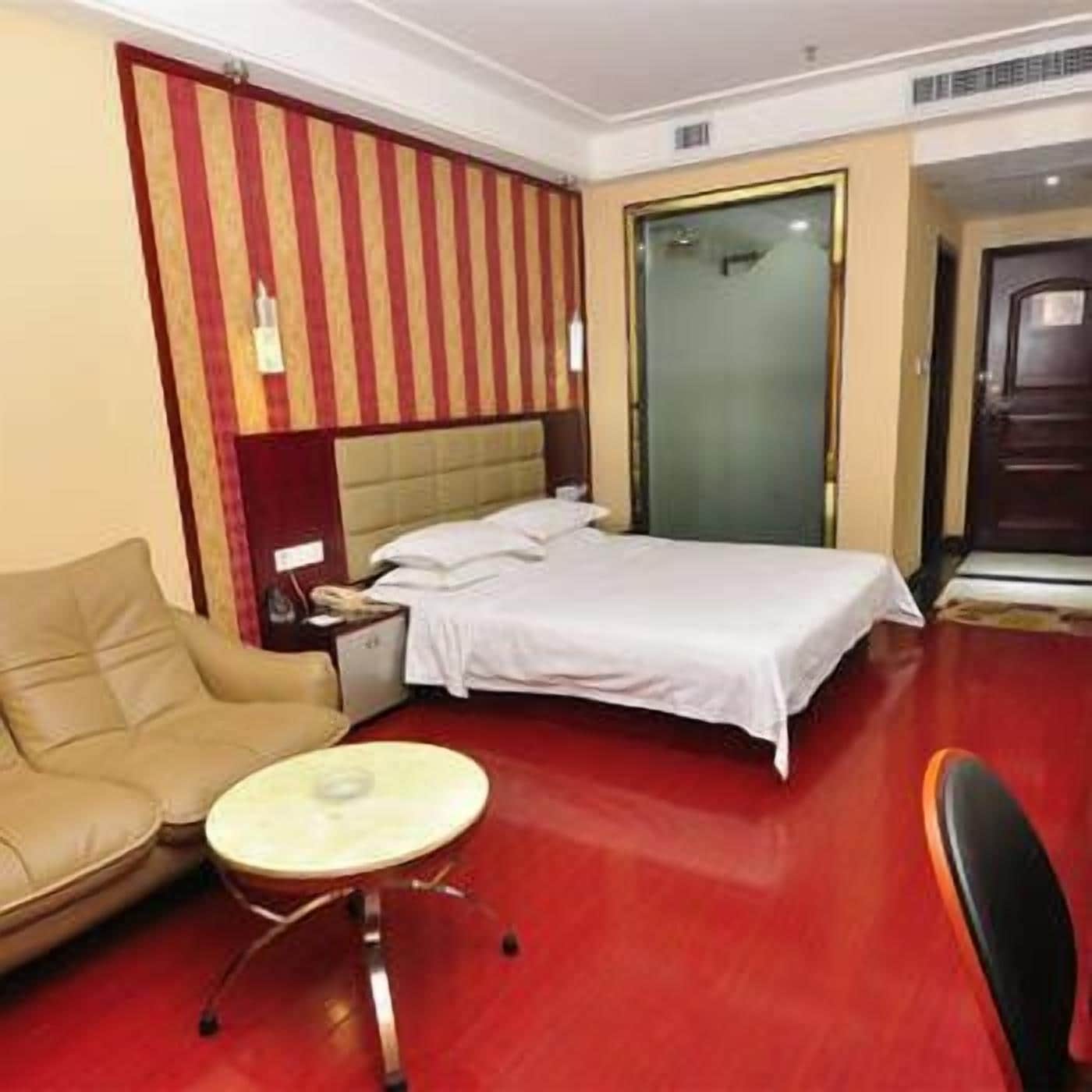 Habitación de hotel con cama, una mesita redonda, un sofá y una puerta que da a otra habitación.