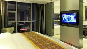 Una habitación de hotel con una cama grande, un televisor en la pared y una ventana con cortinas.