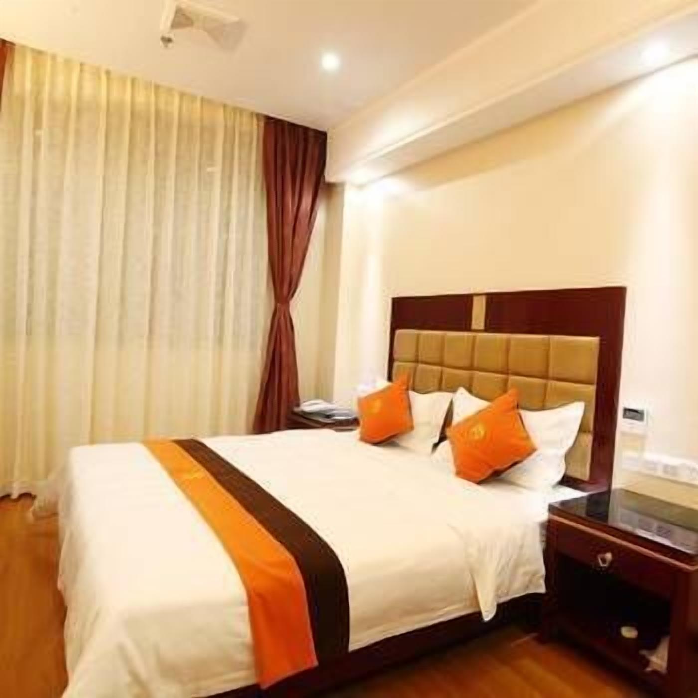 Una habitación de hotel con cama, mesita de noche y ventana con cortinas.