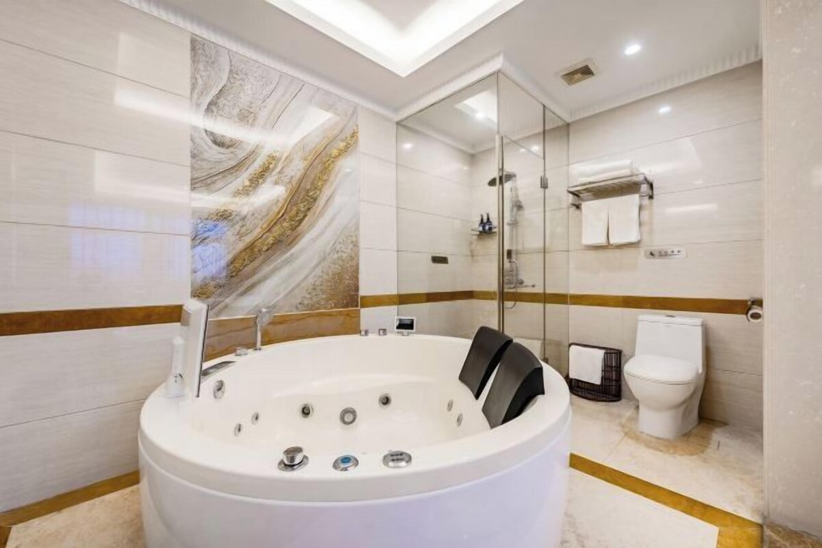 A modern bathroom with a large bathtub, a glass-enclosed shower, and a toilet.