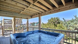 A hot tub on a wooden deck with a view of a residential area and trees.