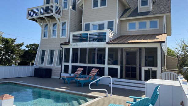 Une maison à plusieurs étages dotée d’une piscine, d’un espace salon extérieur et d’une terrasse couverte.