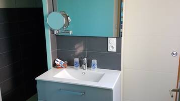 A bathroom with a white sink, a mirror, a teal cabinet, and a blue drawer unit.