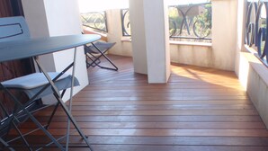 Une terrasse en bois avec une table et des chaises, des colonnes et une balustrade.