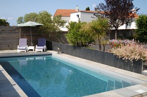 En säsongsöppen utomhuspool, uppvärmd pool och solstolar