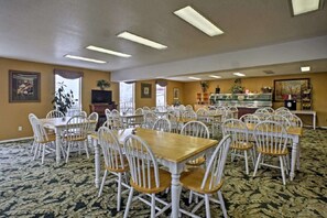 A dining area with multiple tables and chairs, a kitchen area in the background, and a patterned carpet. - Presley's Penthouse 2BR Branson Resort Condo (Branson)