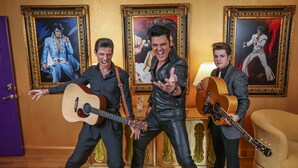 Three individuals in a room with wooden flooring, holding guitars. There are framed pictures on the wall behind them. - Presley's Penthouse 2BR Branson Resort Condo (Branson)