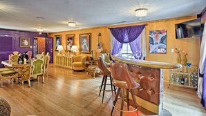 A room with a wooden floor, a dining table with chairs, a bar area with stools, and a television mounted on the wall. - Presley's Penthouse 2BR Branson Resort Condo (Branson)