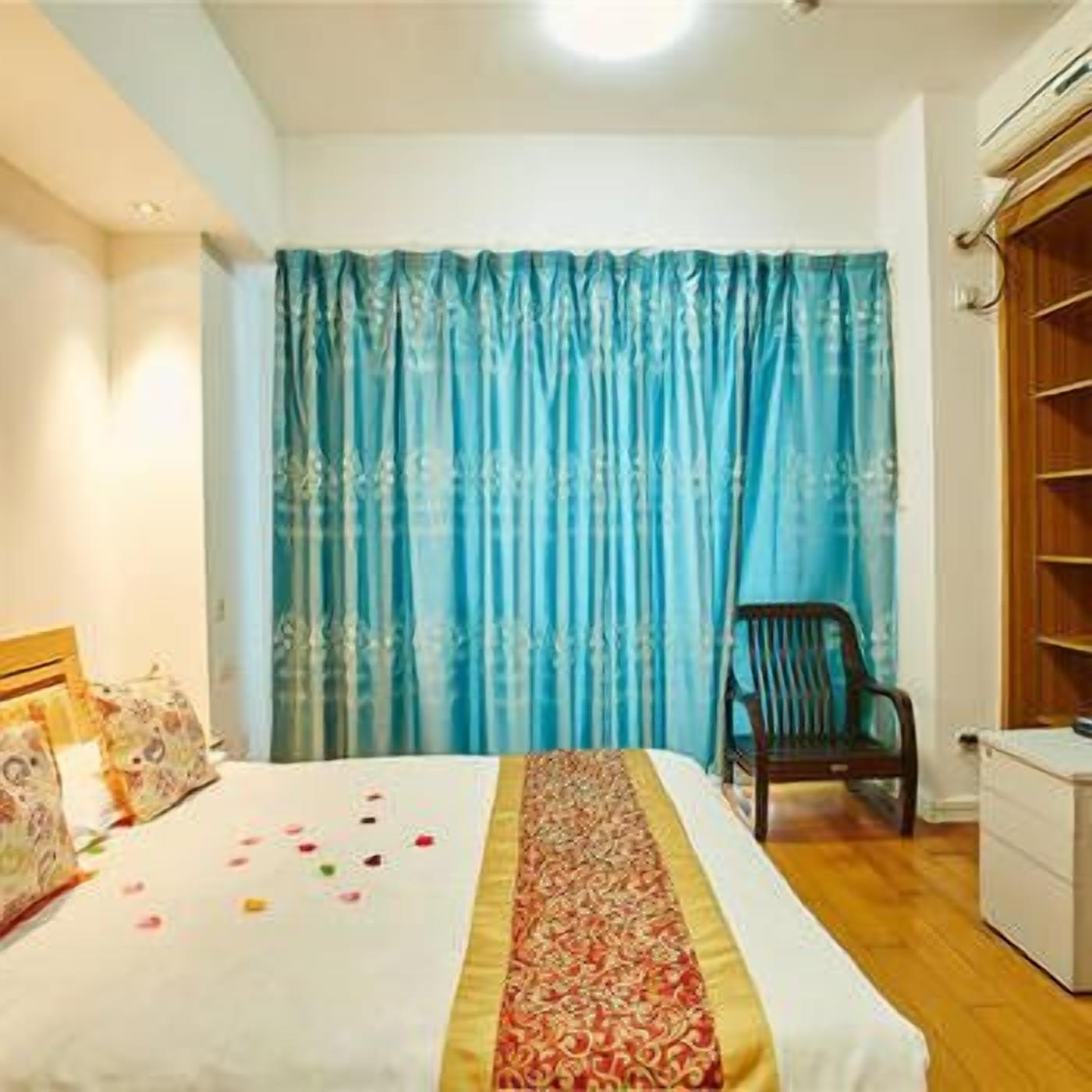 A bedroom with a bed, a chair, a wardrobe, and a curtain.