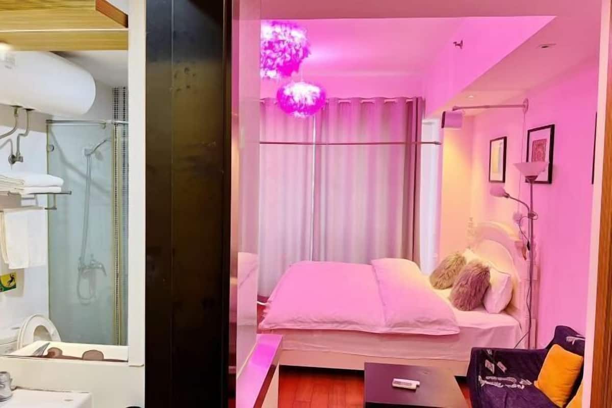 A bedroom with a bed, a nightstand, a lamp, and a window with curtains.