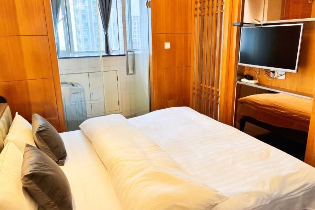 A hotel room with a bed, a television, and a window with curtains.