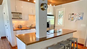 Een moderne keuken met witte kasten, een houten aanrecht en een inbouw eiland met barstoelen.