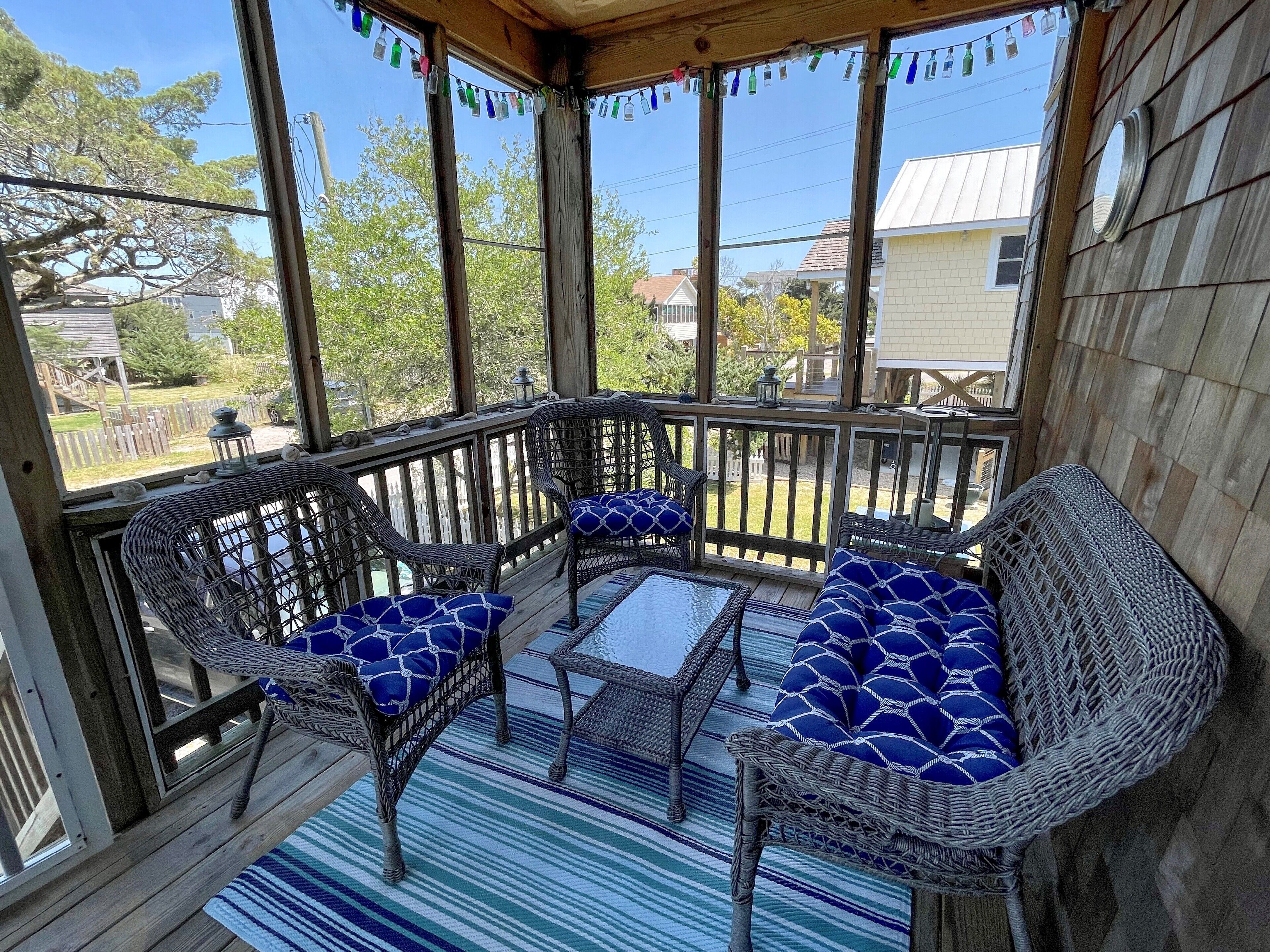 A covered porch with wicker furniture and a striped rug.