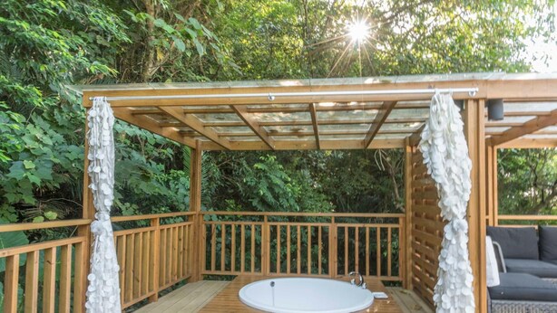 A wooden deck with a hot tub, surrounded by lush greenery. - Crossing The Rainbow Bridge B&B (Xiulin)