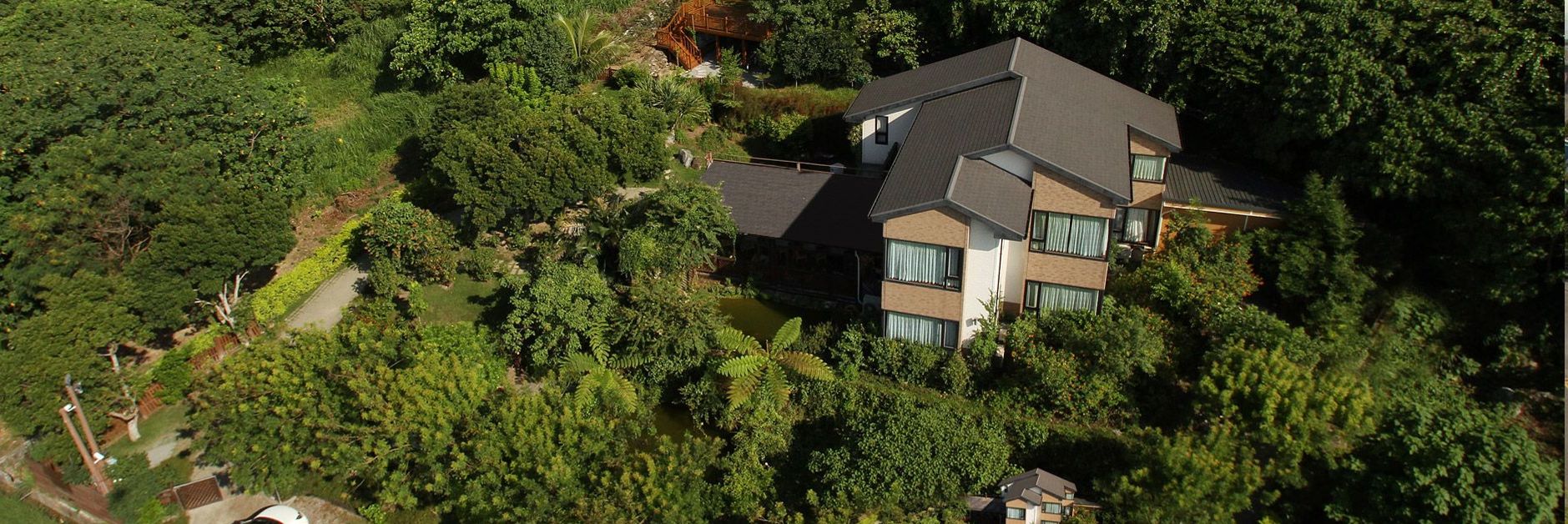 A modern multi-story house surrounded by dense greenery.