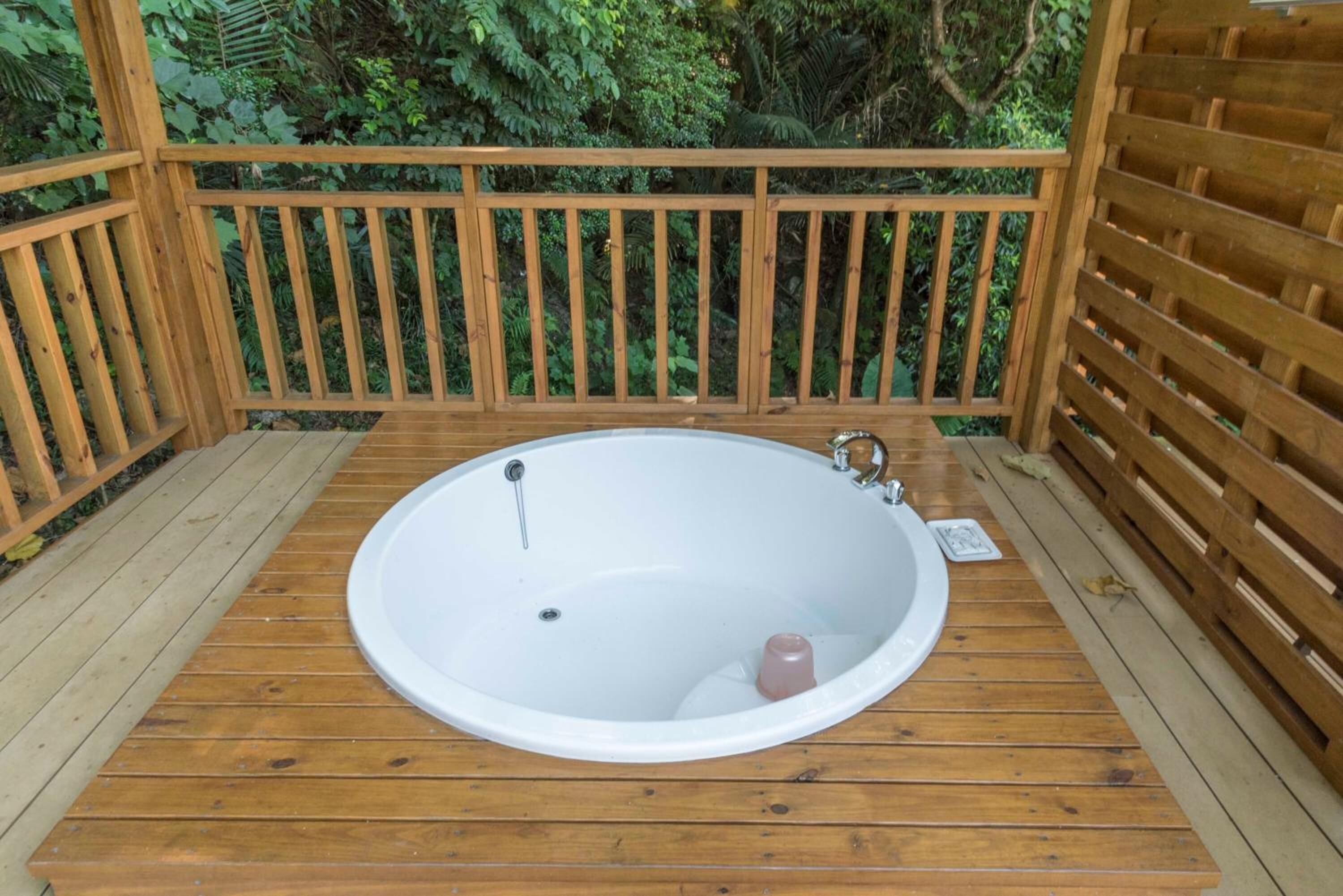 A wooden deck with a large oval bathtub.
