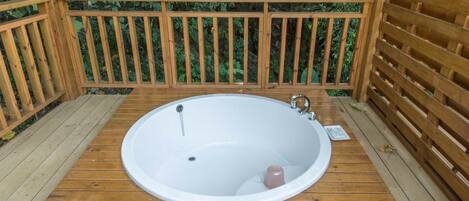 A wooden deck with a large oval bathtub.