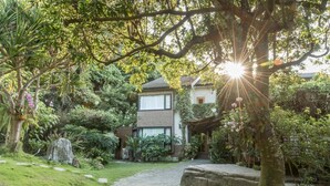 A modern two-story house surrounded by lush greenery and a stone pathway. - Crossing The Rainbow Bridge B&B (Xiulin)