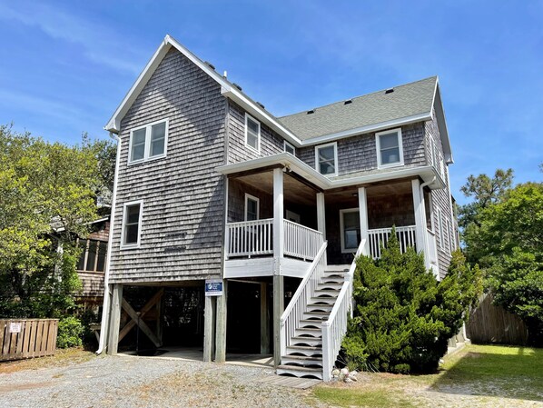 A two-story house with a porch and a staircase leading to the second floor. - Redbeard's Claim: Professionally decorated, perfect relaxing island home. (Ocracoke)