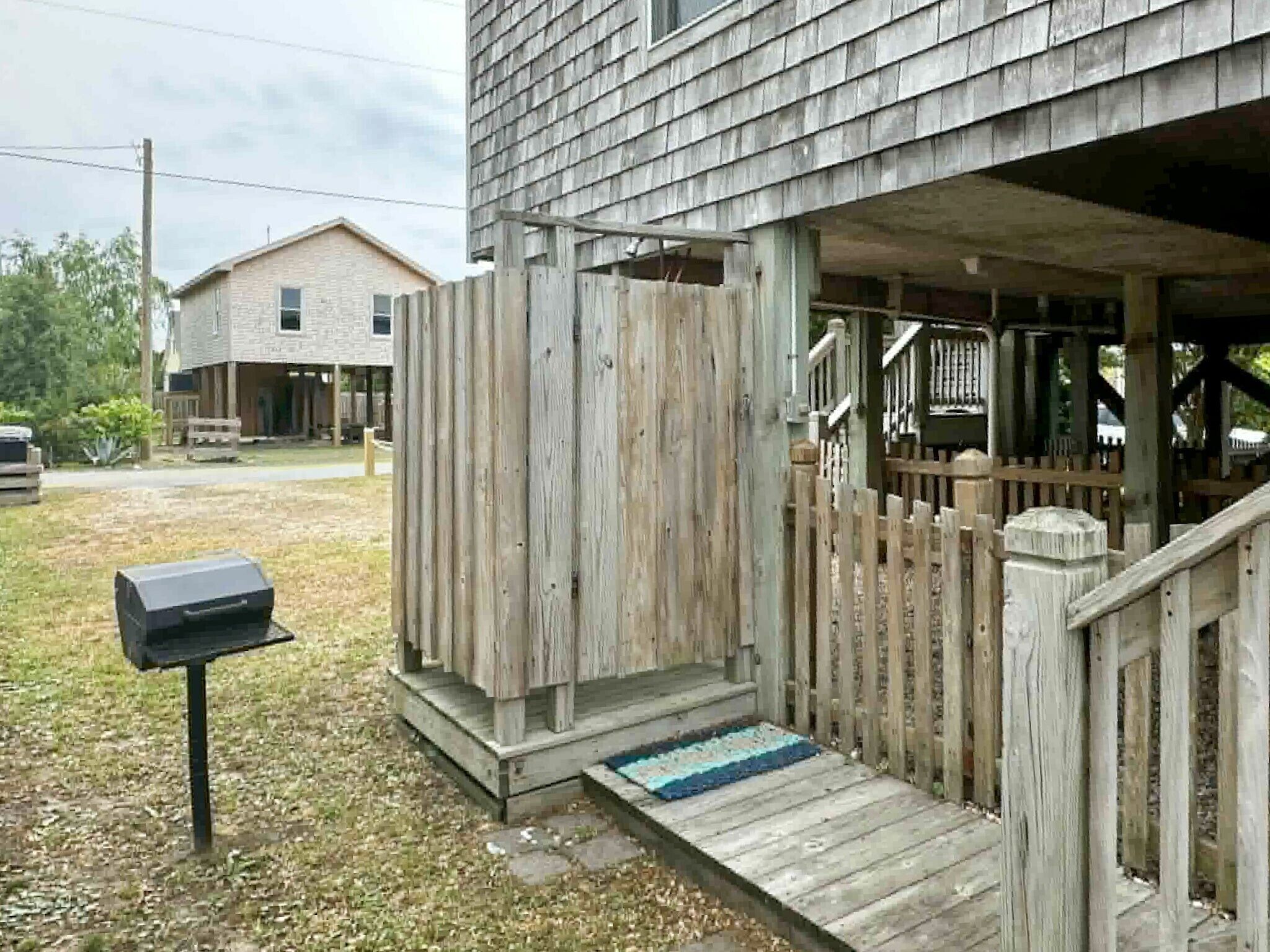 A wooden porch with a mailbox, a wooden fence, and a building in the background.