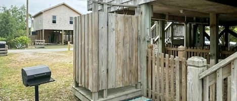 A wooden porch with a mailbox, a wooden fence, and a building in the background.