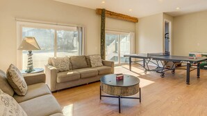 A spacious living room with a sofa, coffee table, and ping pong table.