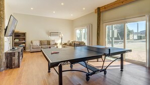A spacious room with a ping pong table, a sofa, a TV, and a bookshelf.