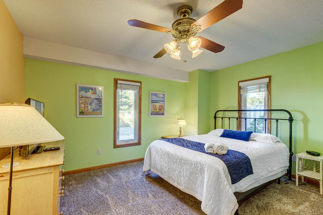 Quarto com cama, ventilador de teto, mesa de cabeceira e janela.