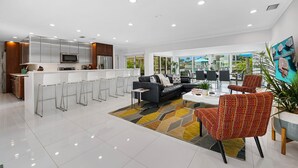 A modern living room with a black leather sofa, white chairs, and a colorful rug.