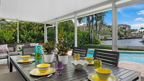 A dining area with a view of a swimming pool and palm trees.