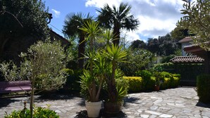 A stone-paved courtyard with potted plants and a bench. - Posada Soano (Arnuero)