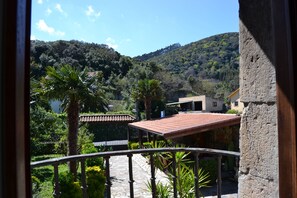 A balcony with a stone floor, surrounded by greenery and a view of a hillside. - Posada Soano (Arnuero)