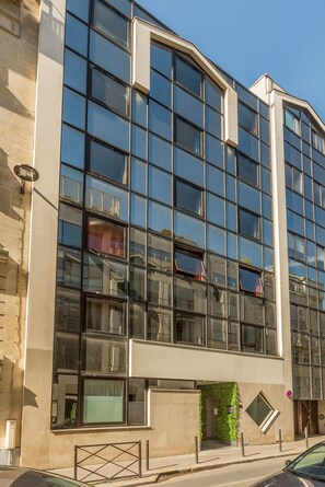 A modern building with large windows, a stone facade, and a gated entrance. - Edgar Suites Expo Paris Porte de Versailles (Paris)